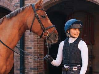 Rider wearing a navy Racesafe Motion3 body protector, holding a chestnut horse 