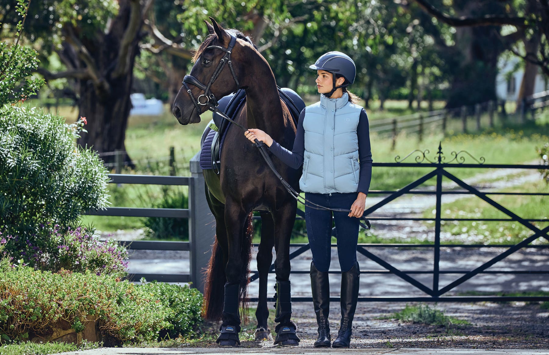 Model wearing Dublin clothing standing with horse outside a gate