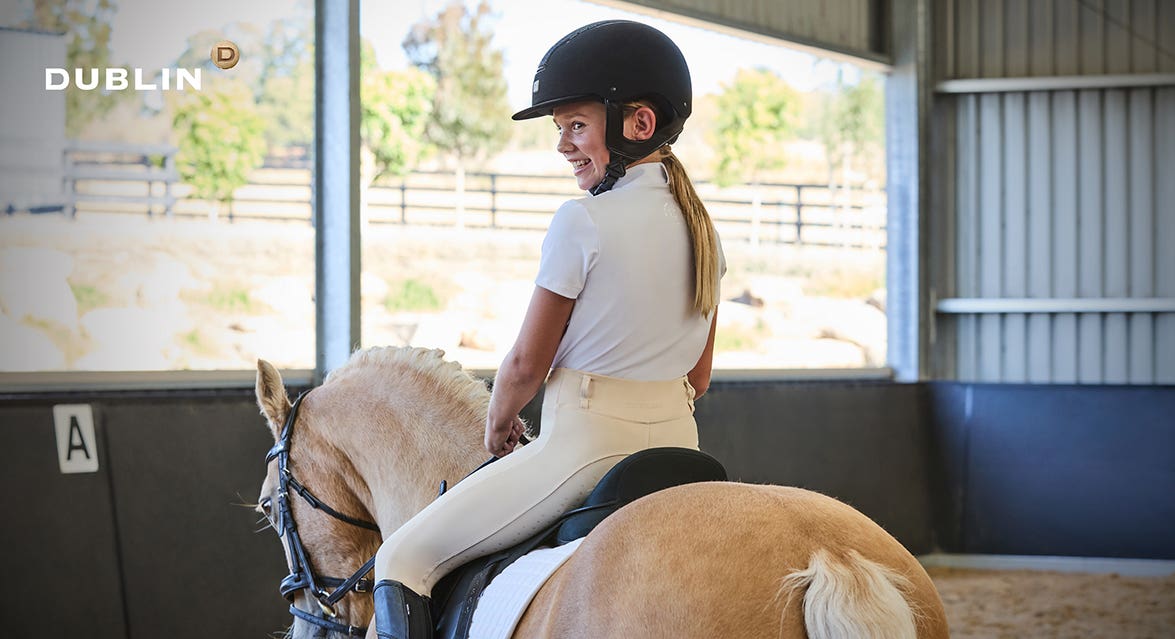 Young girl riding pony wearing Dublin competition clothing