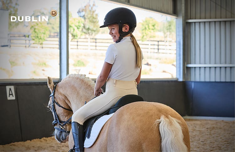 Young girl riding pony wearing Dublin competition clothing