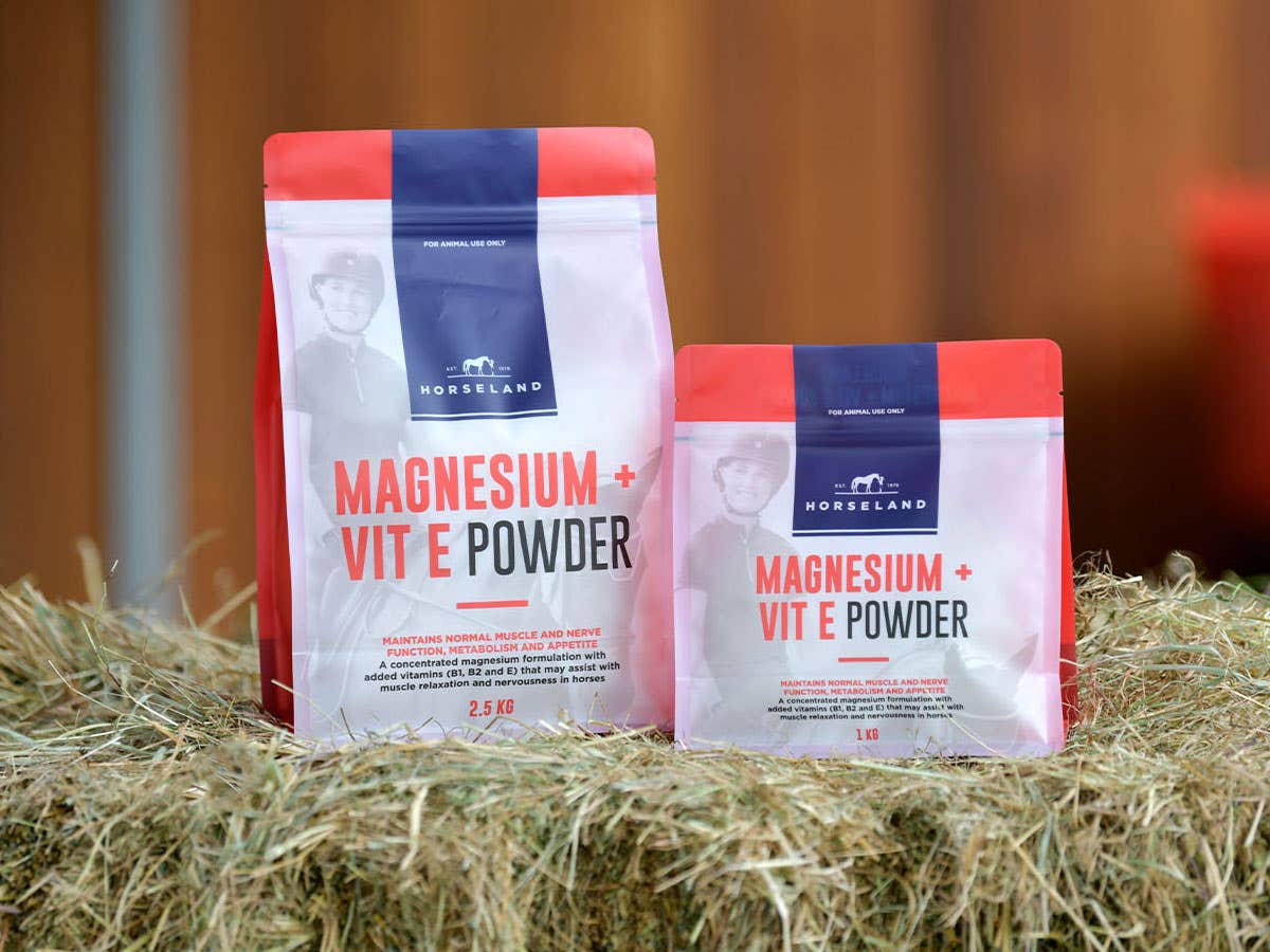 Horseland Magnesium + Vitamin E Powder sitting on hay bales