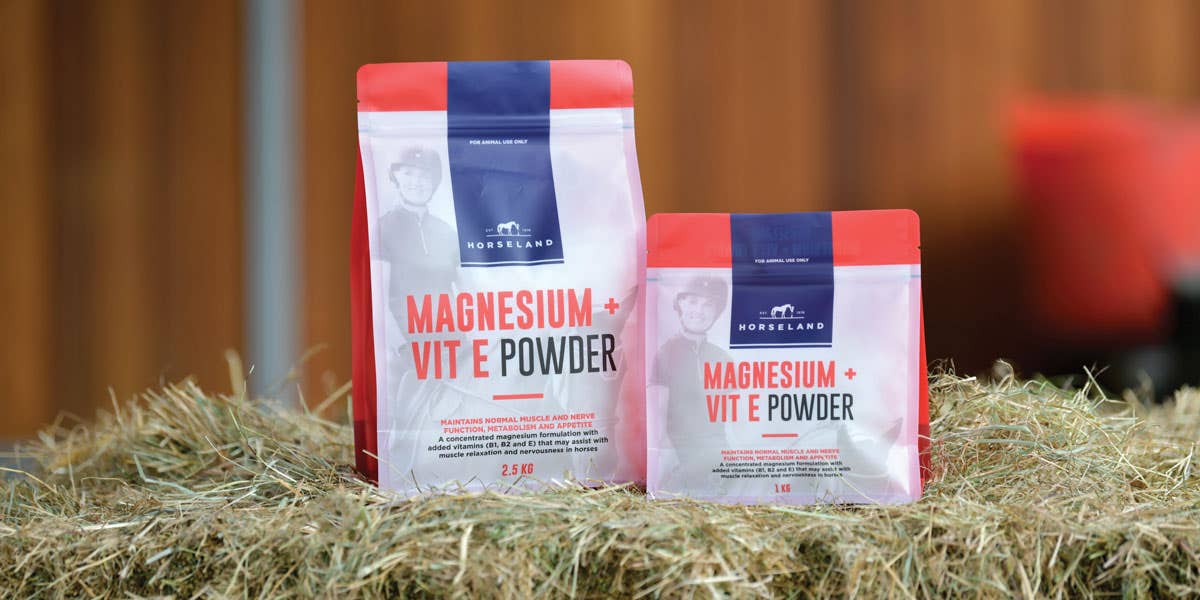 Horseland Magnesium + Vitamin E Powder sitting on hay bales
